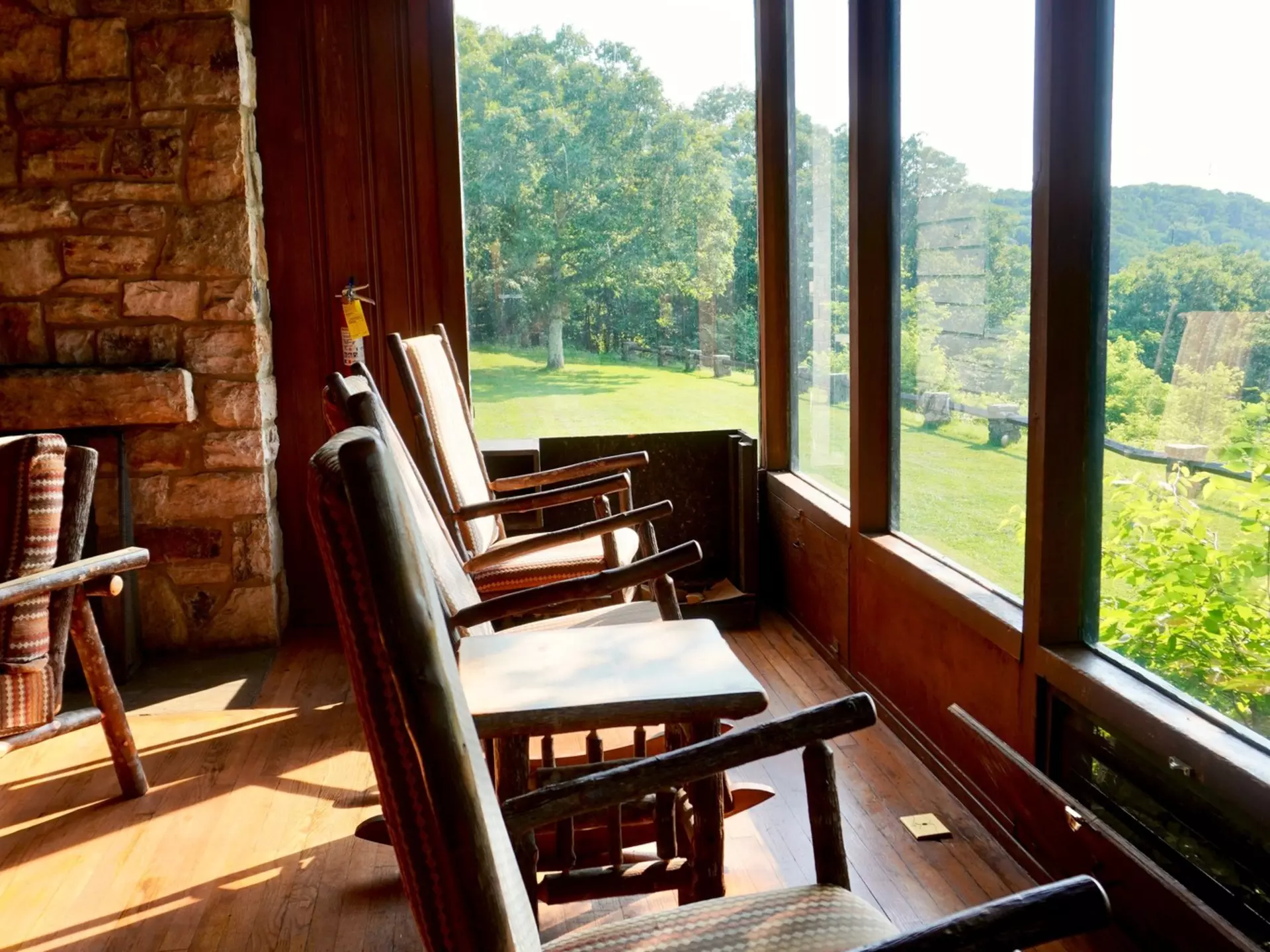 Rocking chairs in a wood-paneled room facing a green landscape.
