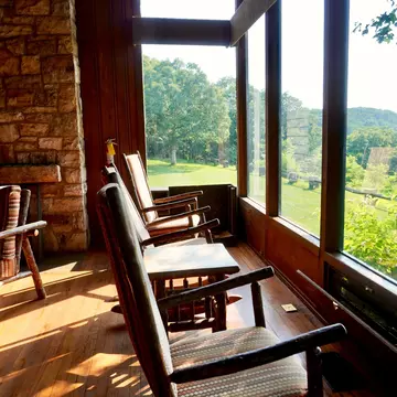 Rocking chairs in a wood-paneled room facing a green landscape.