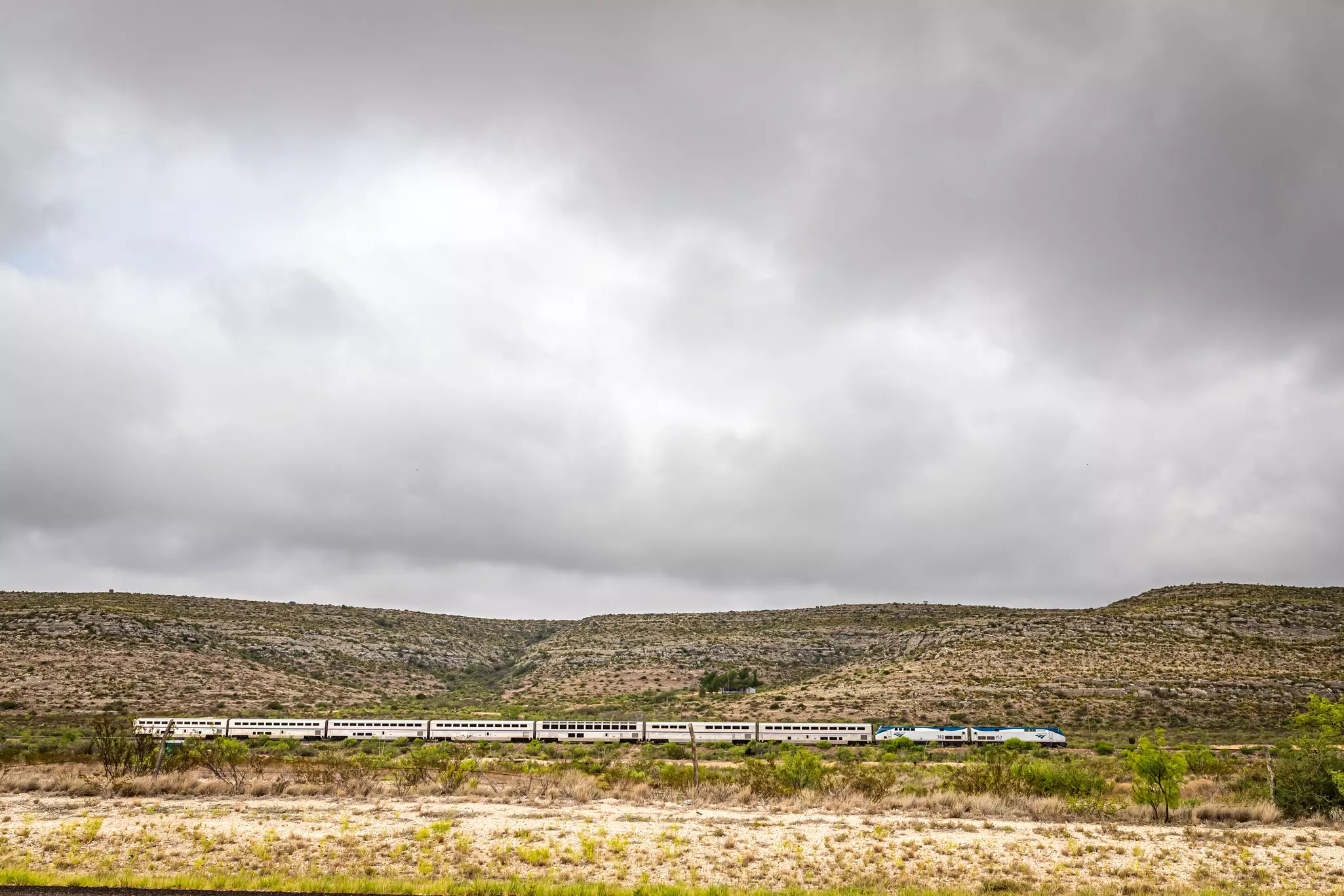 The Amtrak Sunset Limited train travels through the desert under a moody sky near Sanderson, Texas.