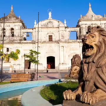 A lion statue outside a squat cathedral with square bell towers