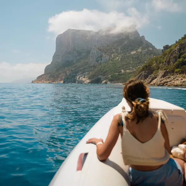 Tourist enjoying breathtaking view of sardinian coastline from a boat near baunei