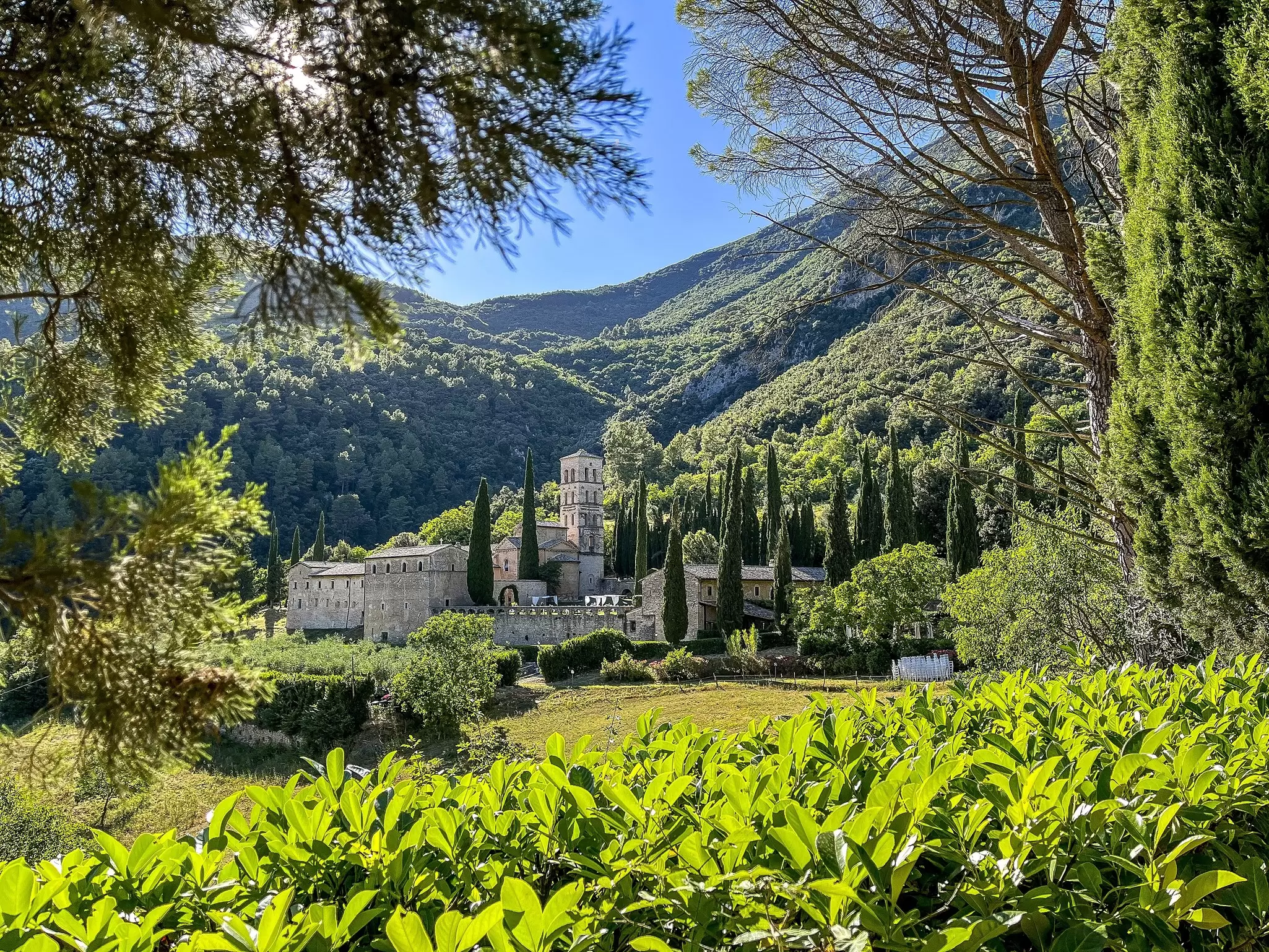 A stone building with a tower in a lush countryside setting.