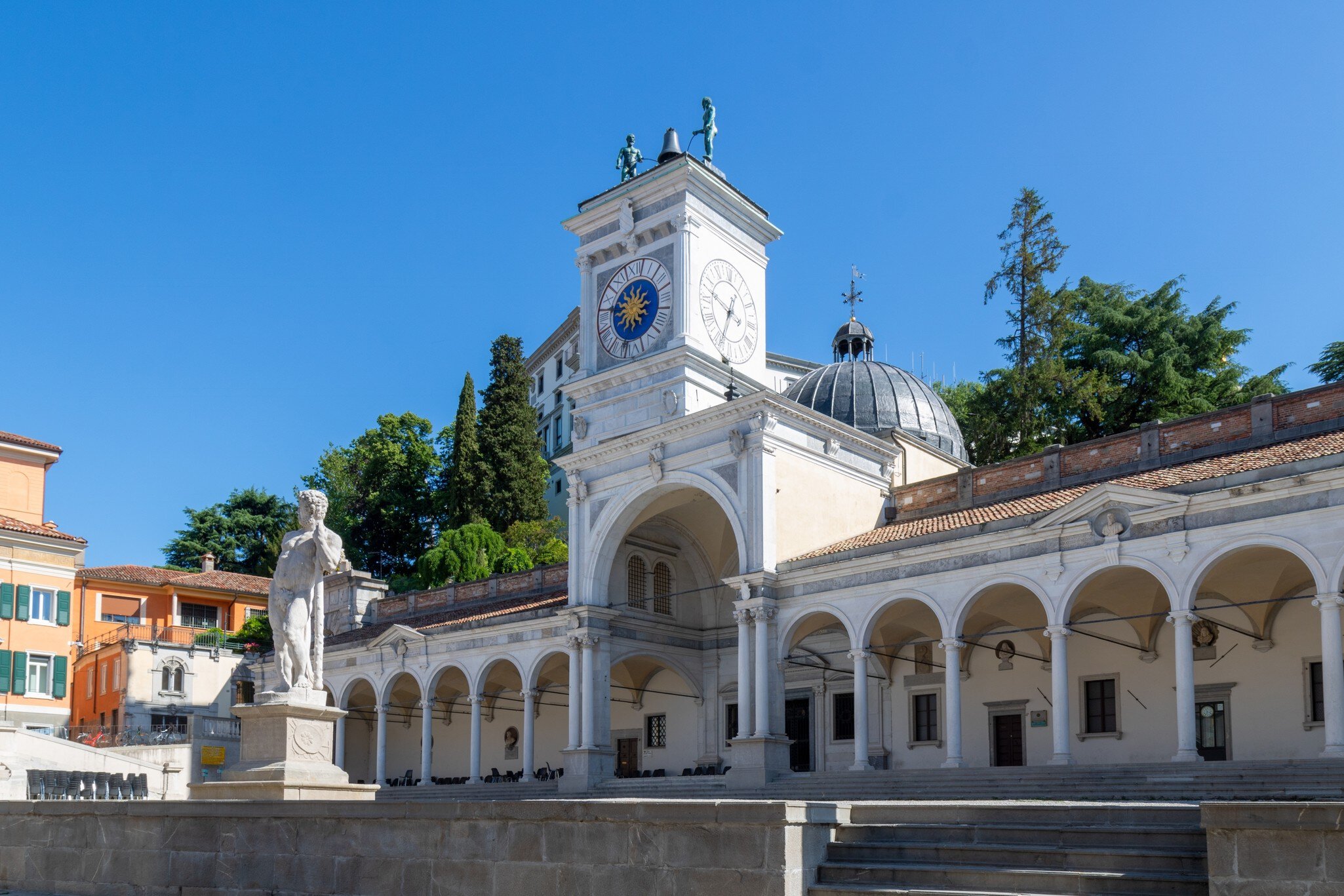 Udine, Italy; July 5 2022: Clock tower, Torre dell'Orologio, in Loggia di San Giovanni located in Piazza della Libertà with a sculpture hitting a bell above the tower.; Shutterstock ID 2275292315;