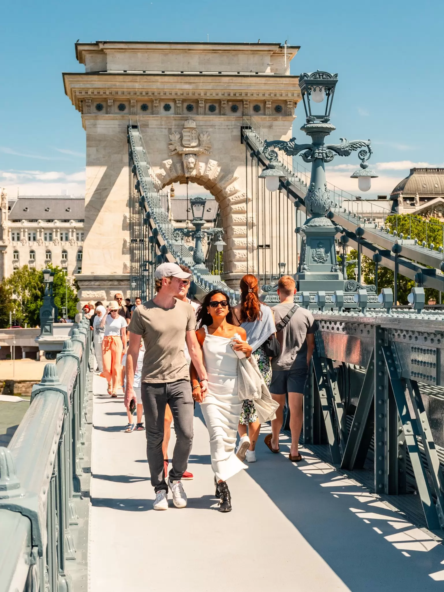 A young couple walks on the Széchenyi Chain Bridge in summer in Budapest, Hungary.
