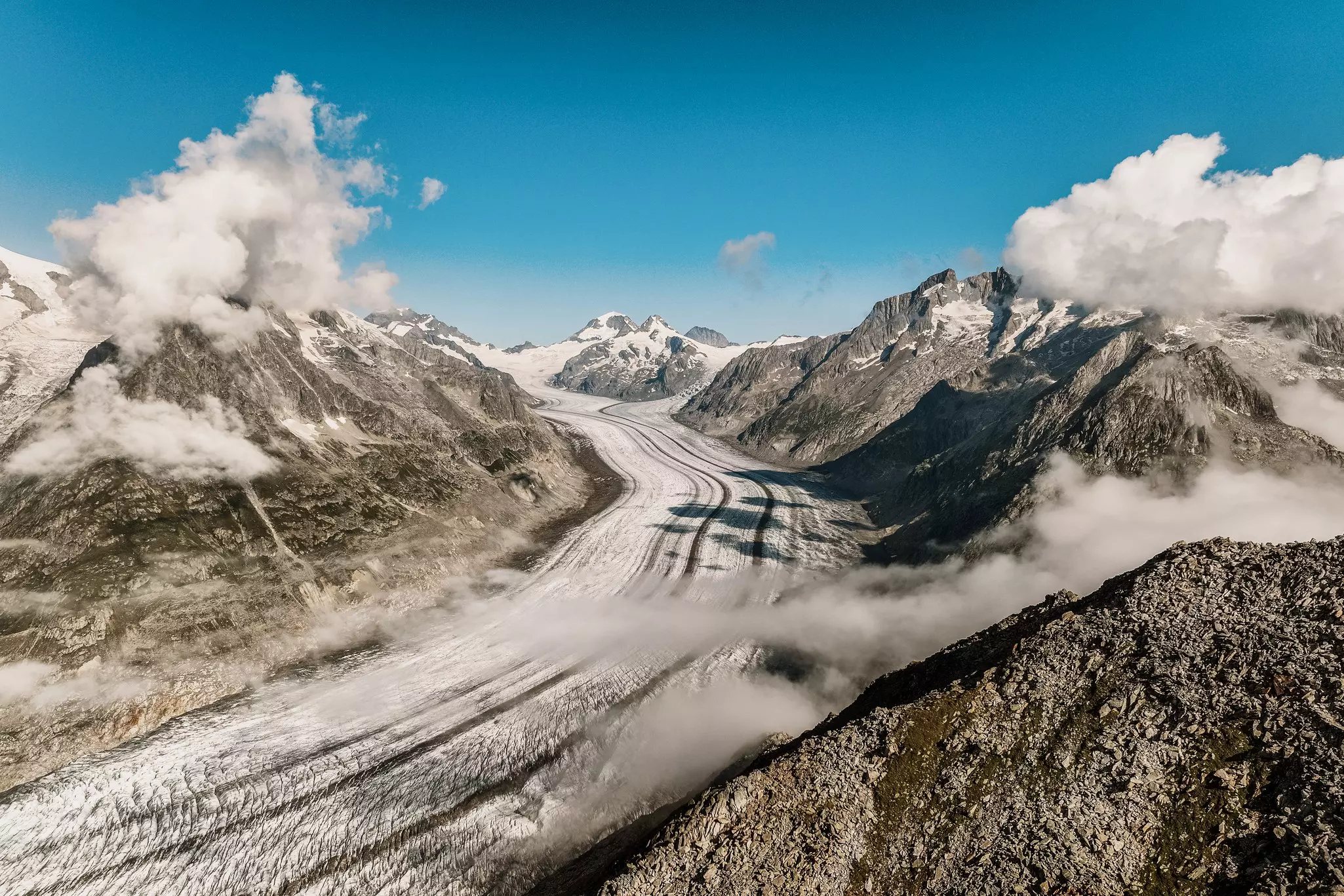 Aletsch Glacier pictured from View Point Eggishorn, with wispy clouds hugging the slopes leading down to the ice, Valais, Switzerland