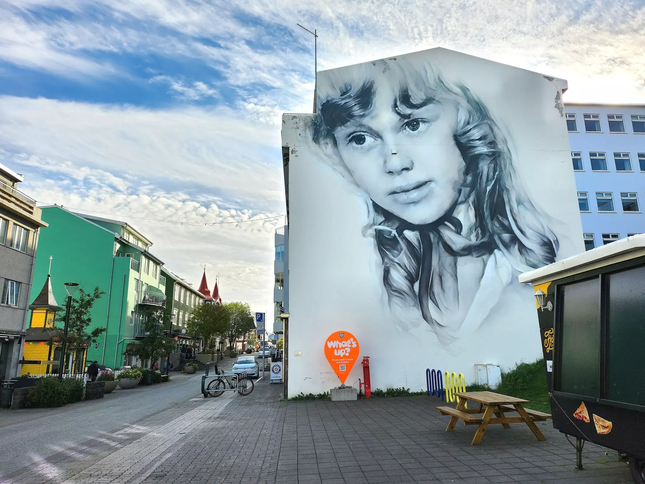 A mural on a wall depicts a young girl on a street in a city.