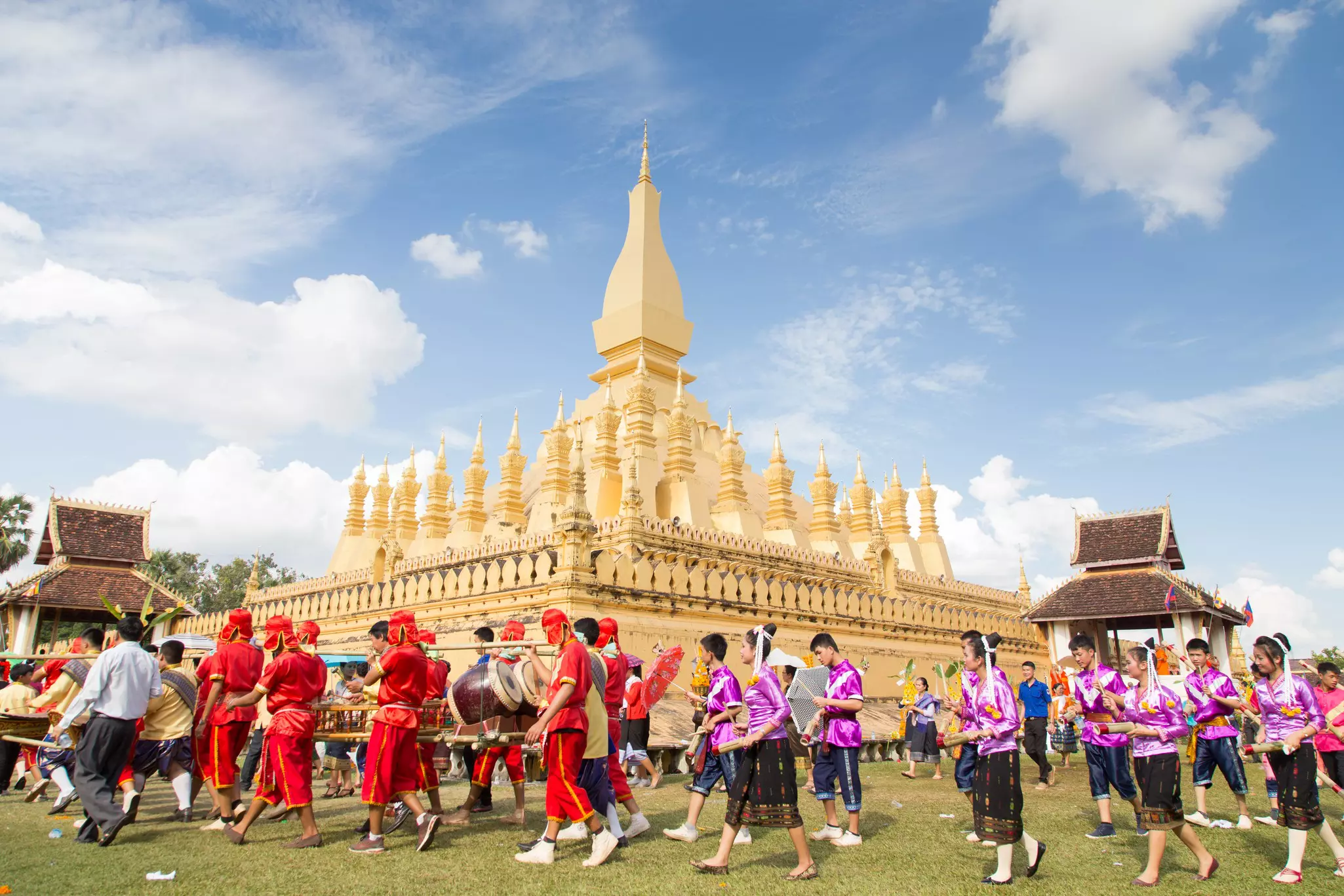 A large golden temple. People in colorful dress walk in a clockwise direction around the outer walls.