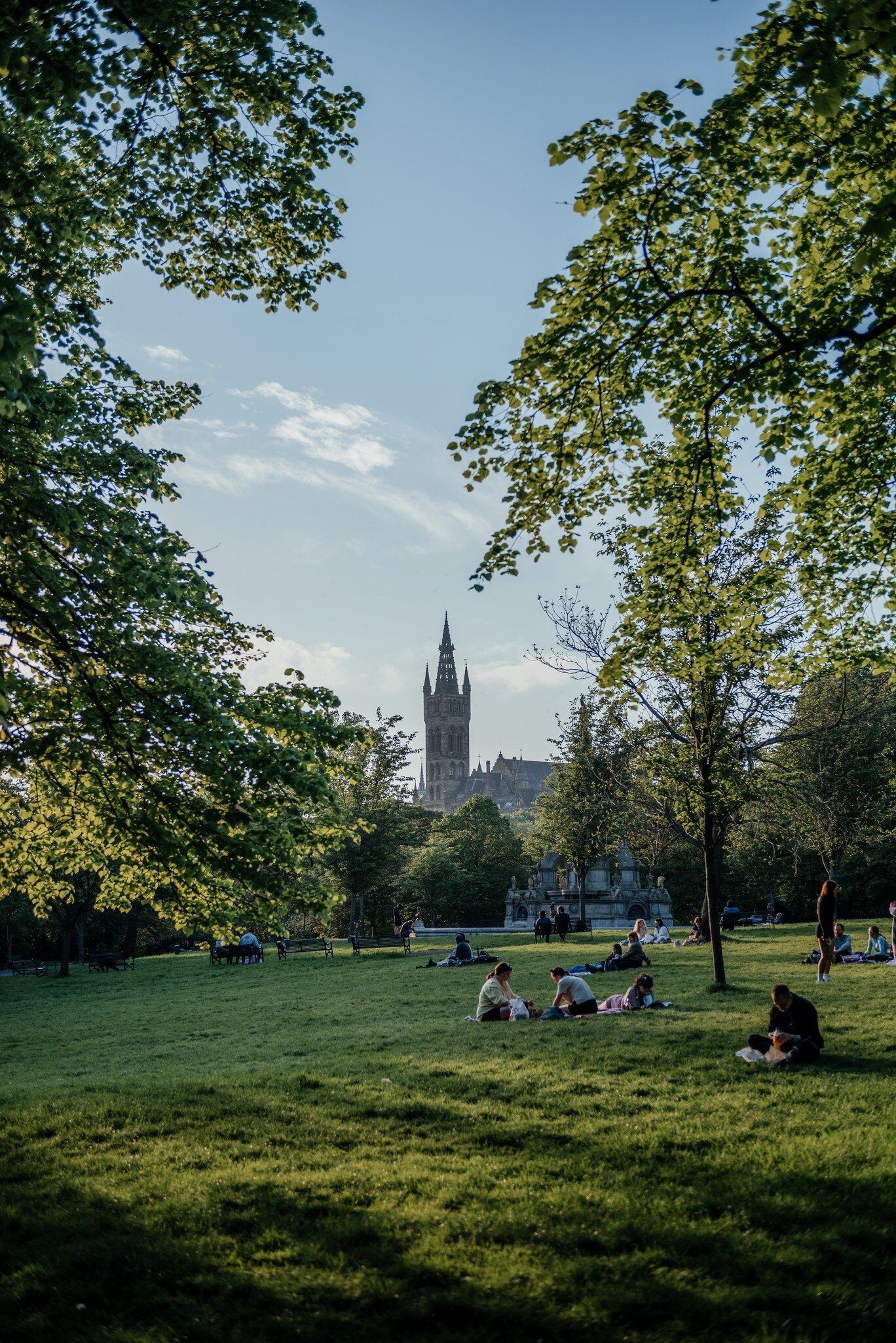 Visitors lying on the grass and enjoying a sunny Day in Kelvingrove Park, Glasgow.