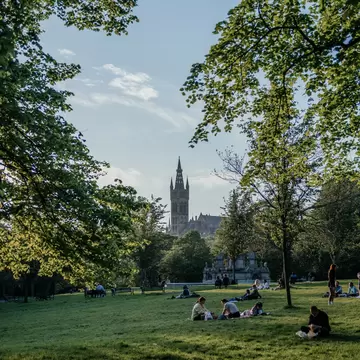 Visitors lying on the grass and enjoying a sunny Day in Kelvingrove Park, Glasgow.