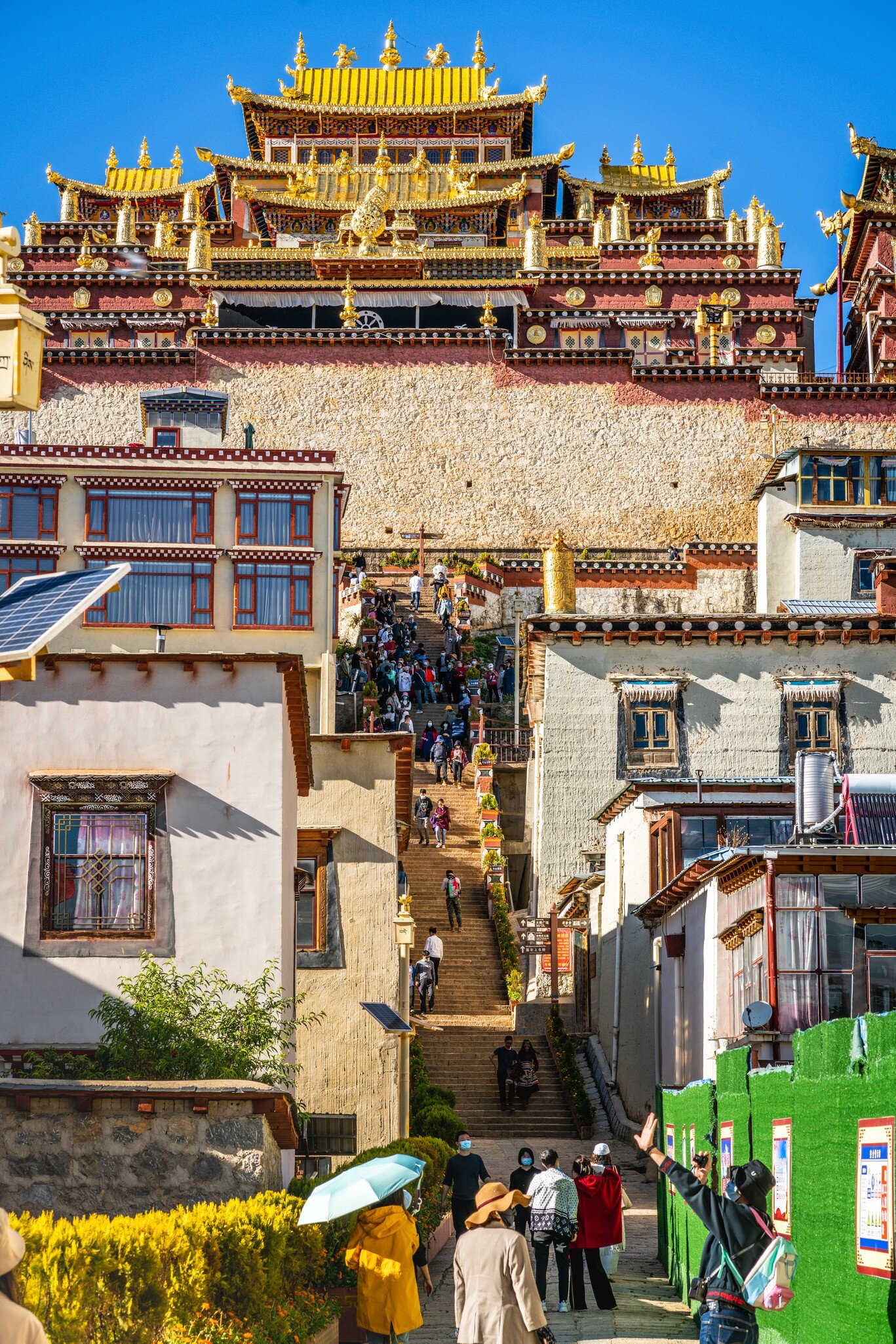 Vertical view of the entrance of Songzanlin monastery with people and sunny blue sky in Shangri-La Yunnan China