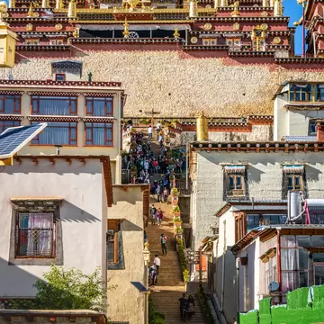 Vertical view of the entrance of Songzanlin monastery with people and sunny blue sky in Shangri-La Yunnan China