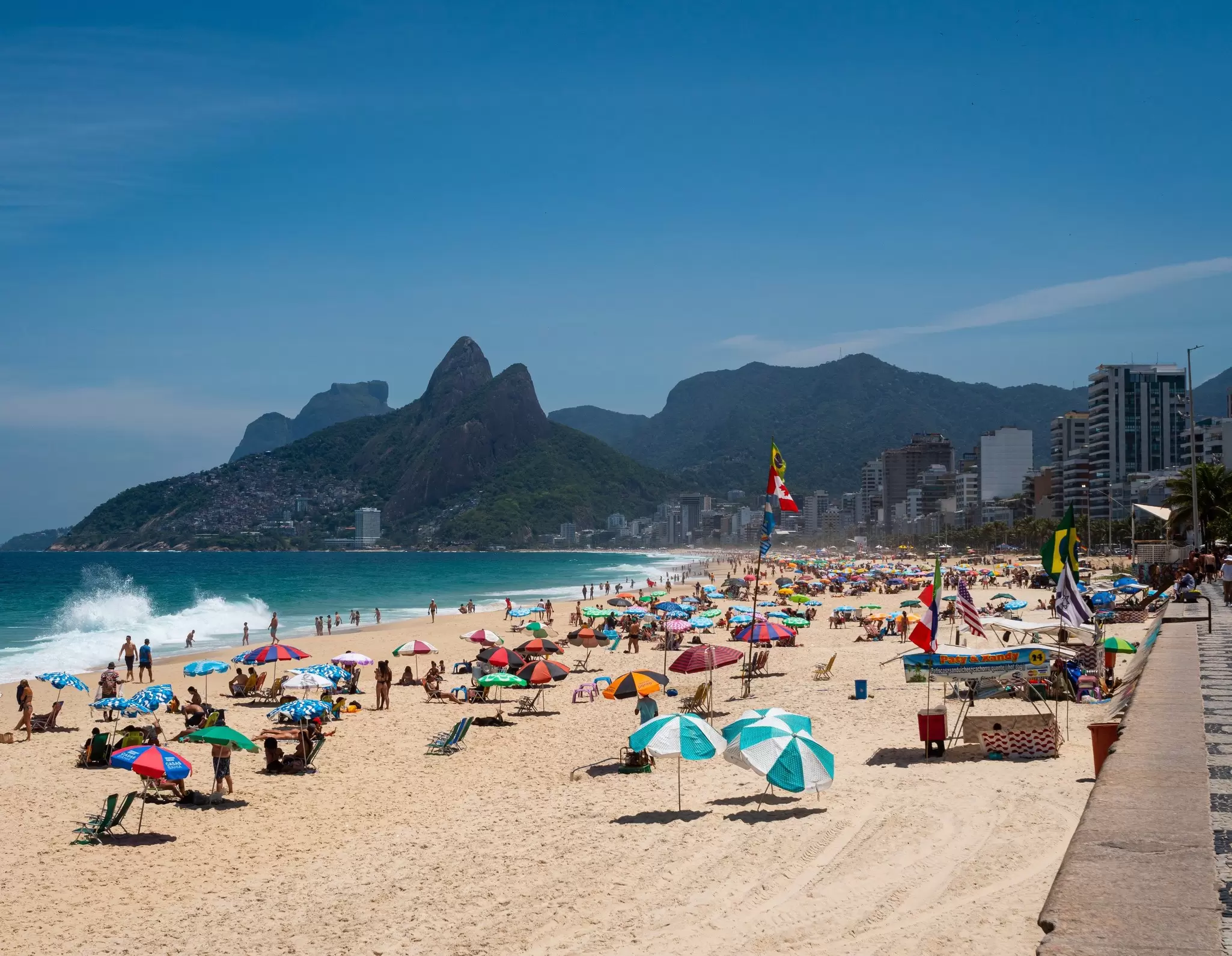 People relax on the iconic Ipanema Beach in Rio de Janeiro, Brazil, looking towards the Dos Hermanos mountains.