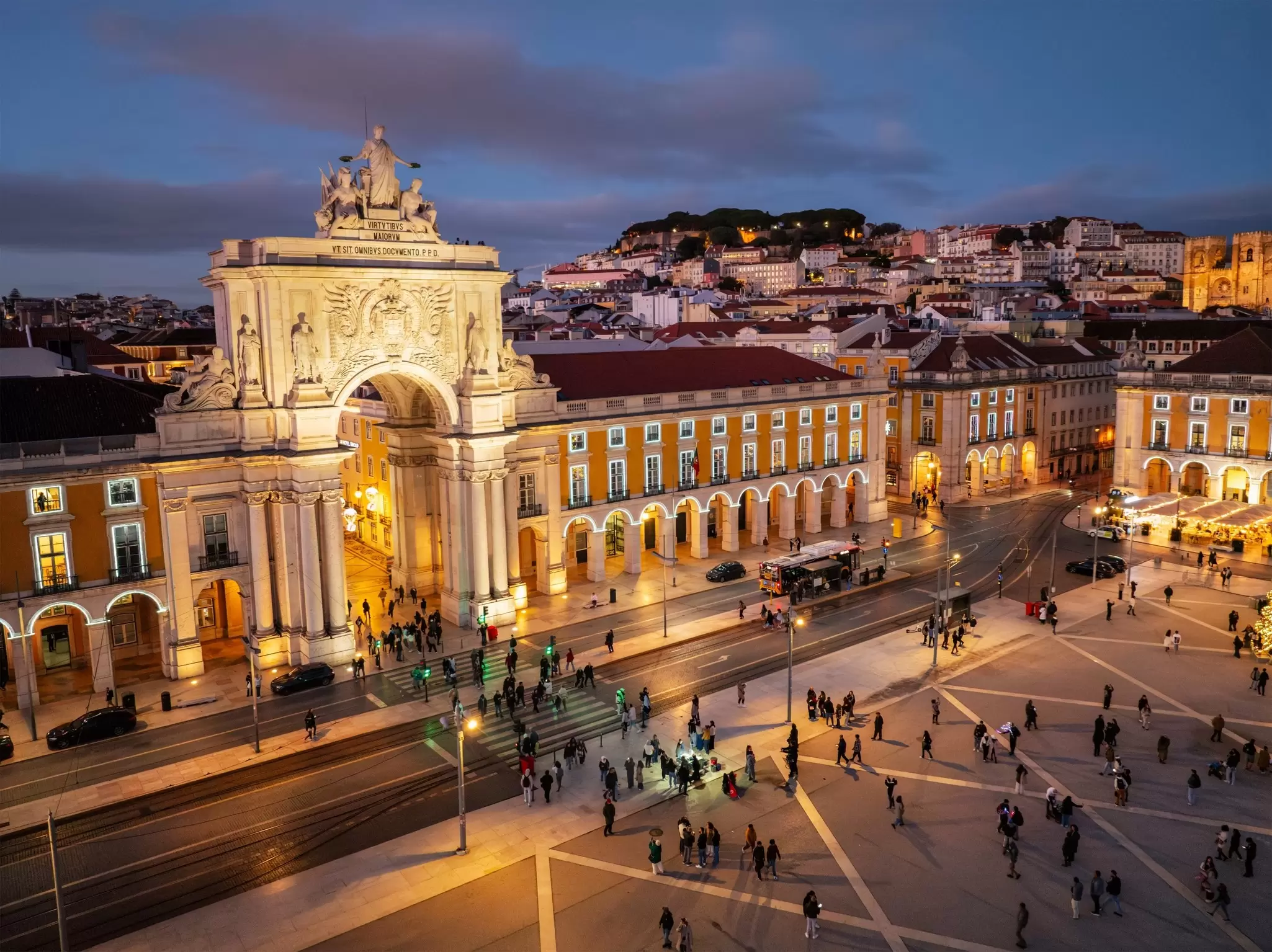 Ornate archway and building next to a plaza that is illuminated at night