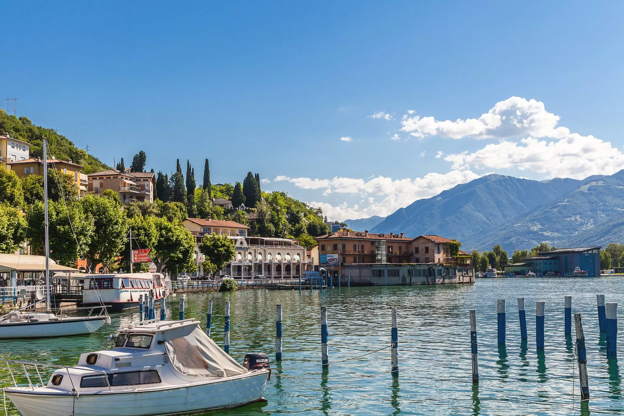 Boats moored along a lakeside waterfront with large homes overlooking the water