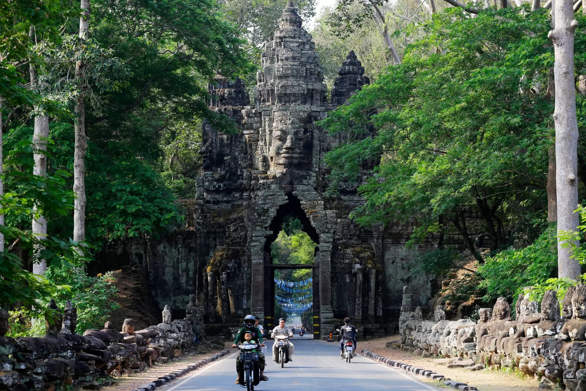 People ride through the North Gate of Angkor Thom, part of Angkor Wat complex.