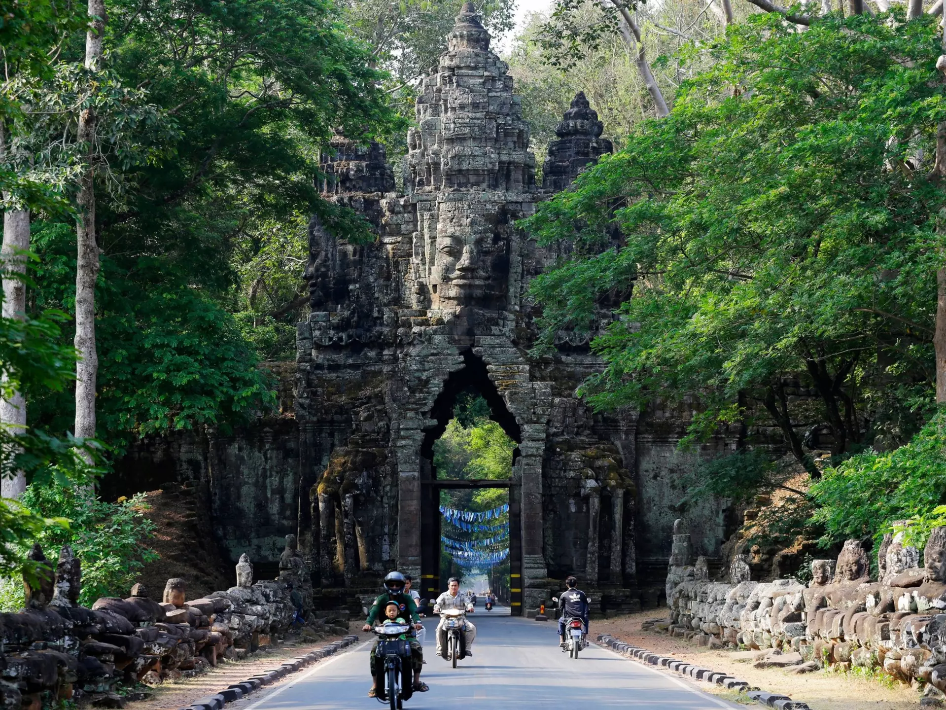 People ride through the North Gate of Angkor Thom, part of Angkor Wat complex.