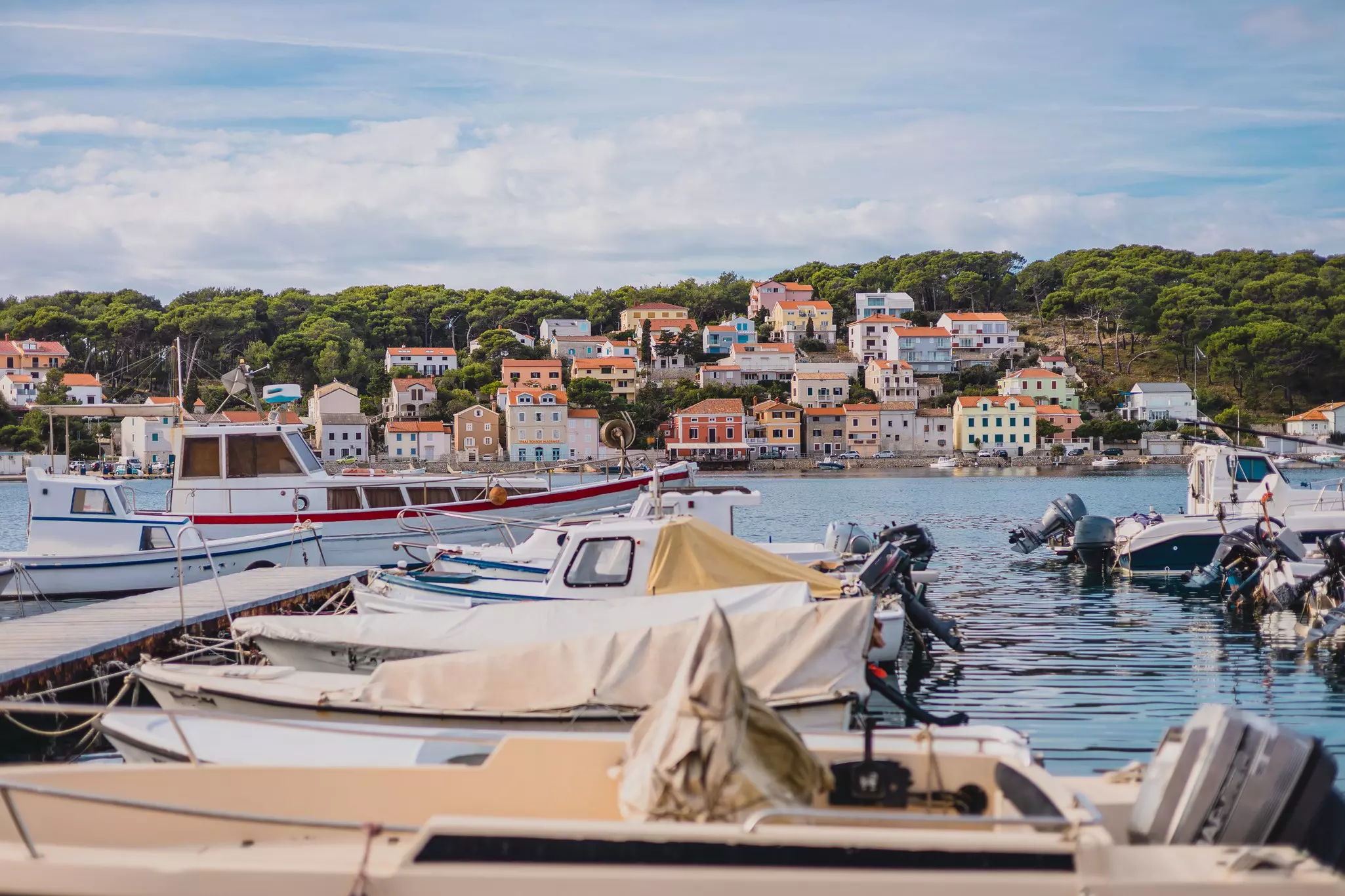 Boats docked in a small harbor. Colorful houses line the water's edge.