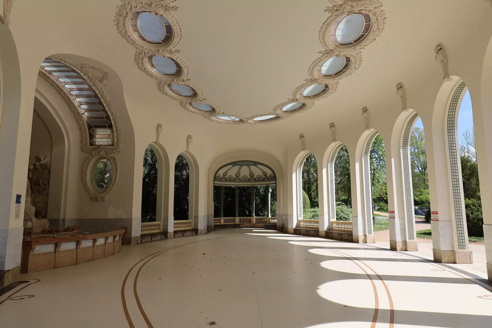 A curved pavilion with a water source to one side