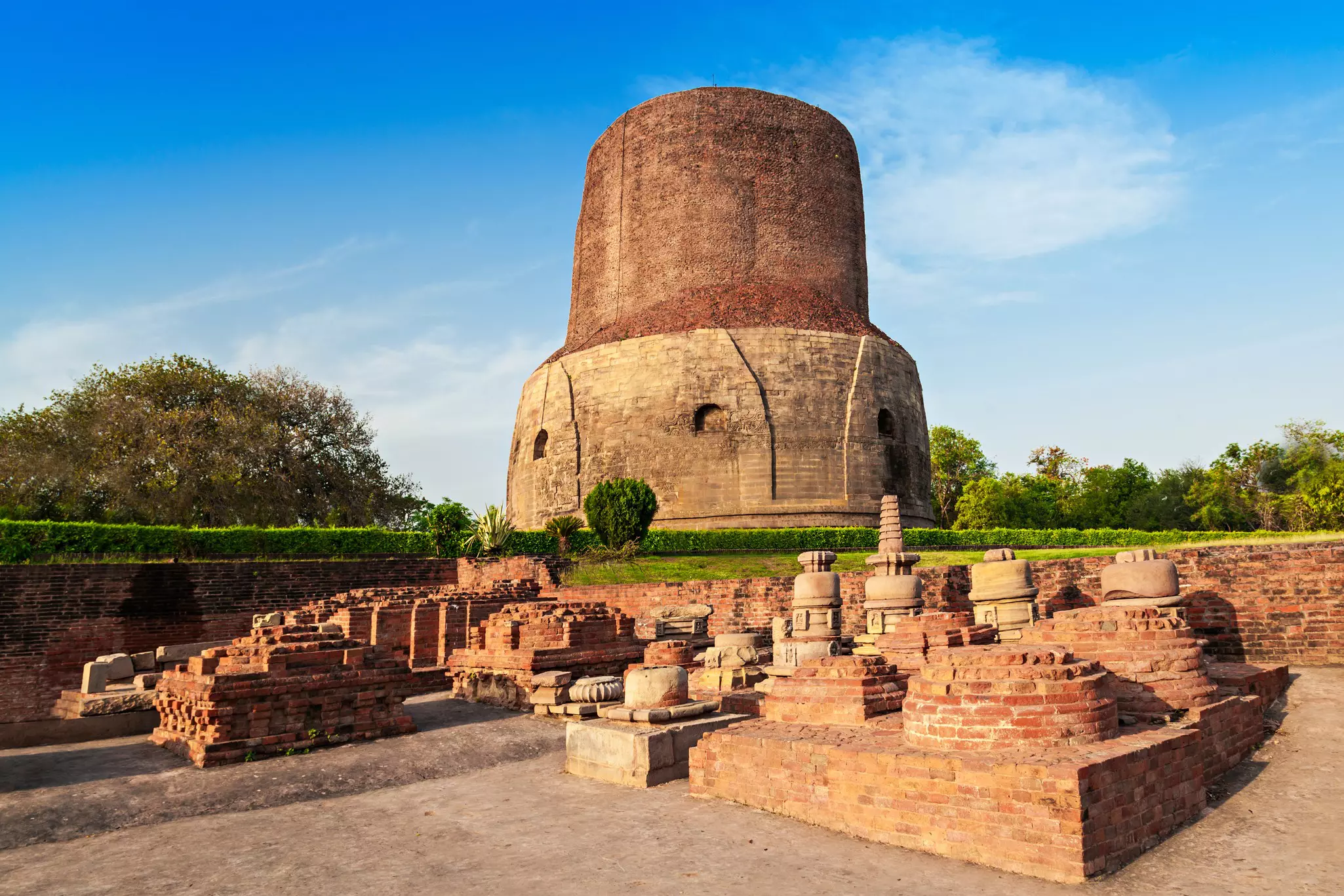 The red-brick base of the Dhamekh Stupa, surrounded by smaller stupas in Sarnath, India. 