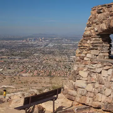A bench at South Mountain Park offers a lookout onto the Phoenix skyline and desert in the distance