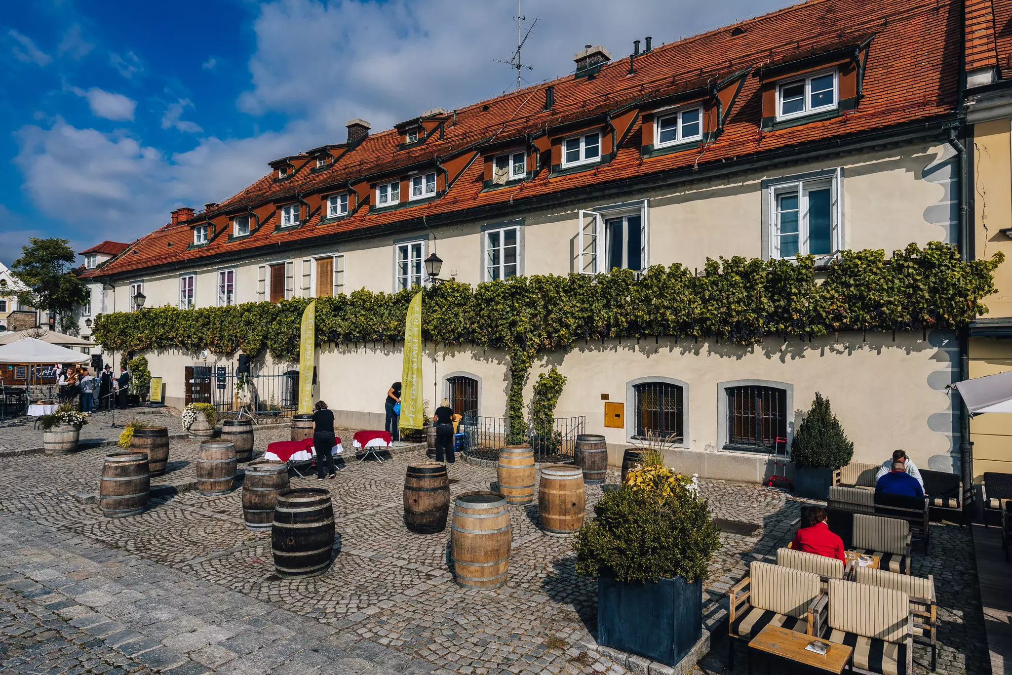 Slovenia's Old Vine House with wine barrels, visitors and seating outside