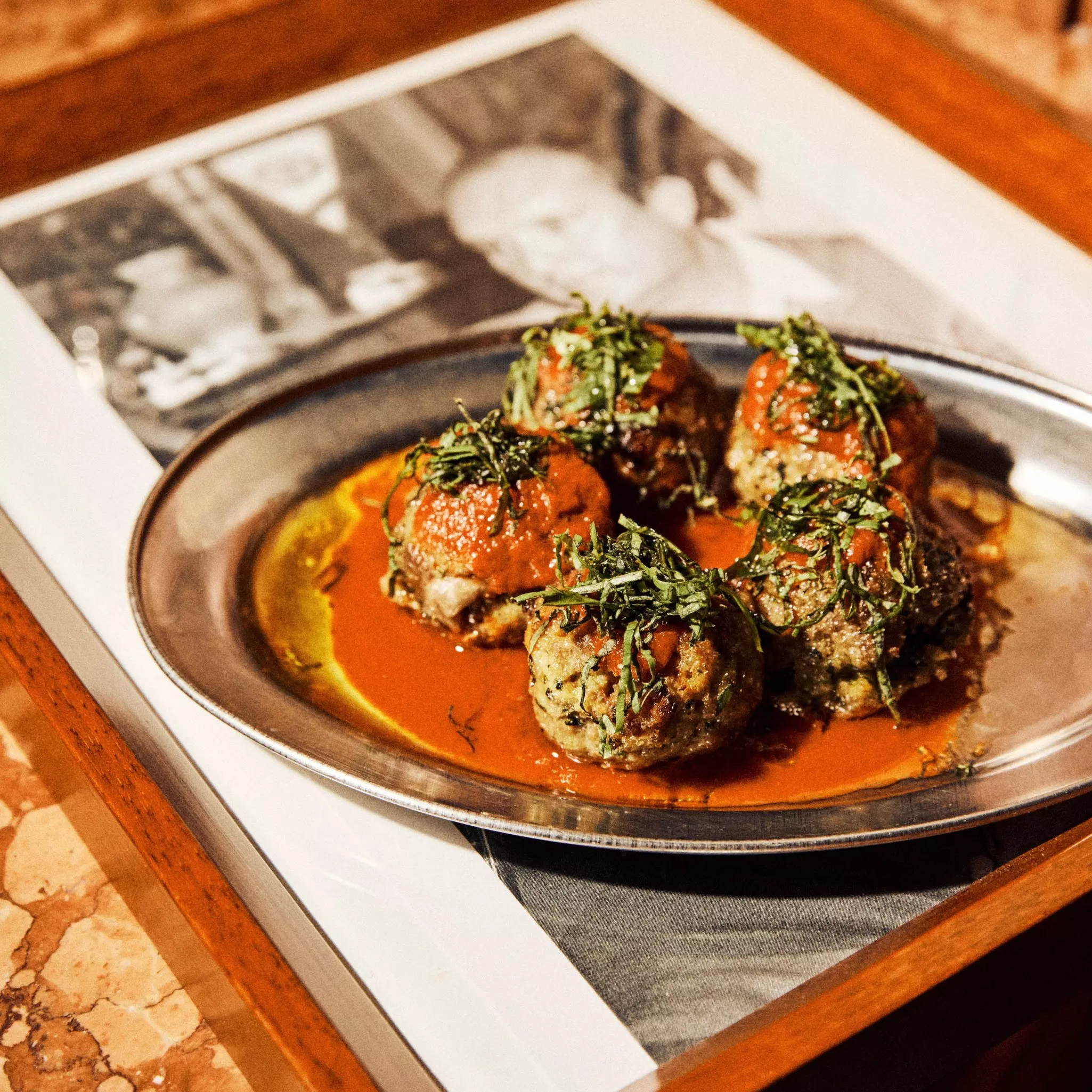 A close-up shot of four meatballs on a plate placed a serving tray at a restaurant