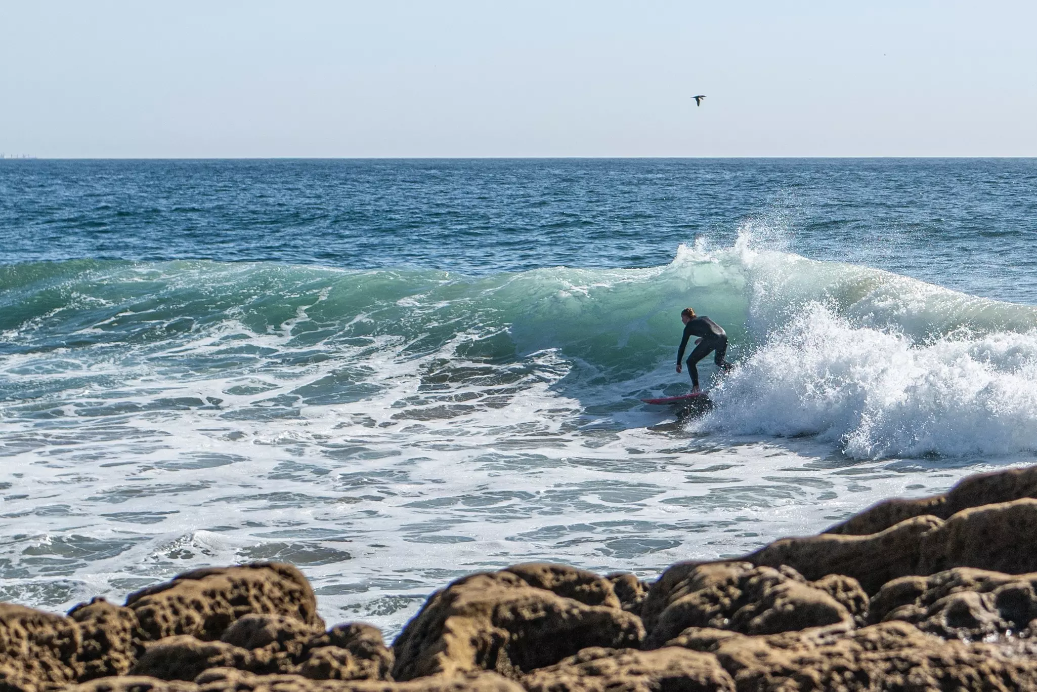 A lone surfer by rocks