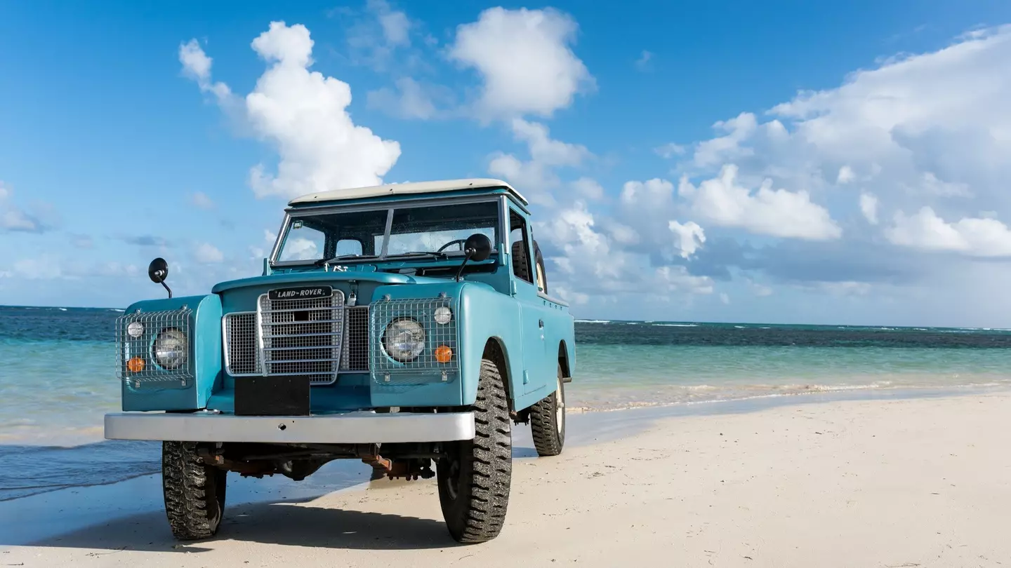An old blue rover is parked on a beach near the water in Las Terranes, Dominican Republic.