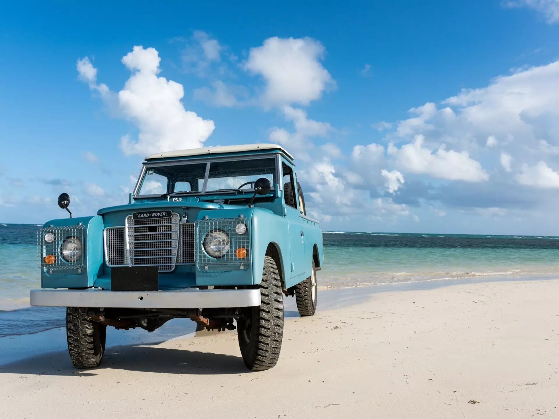 An old blue rover is parked on a beach near the water in Las Terranes, Dominican Republic.