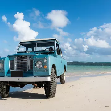An old blue rover is parked on a beach near the water in Las Terranes, Dominican Republic.