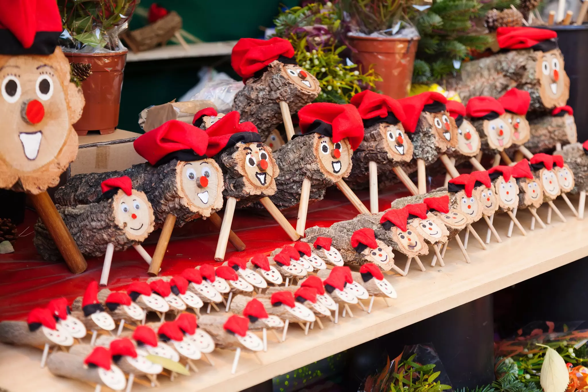 Small wooden logs with a smiling face, legs and a red Christmas hat