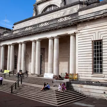 People sitting on the steps of the National Museum and art gallery which is a popular travel destination tourist attraction landmark of the city in Cardiff, Wales.