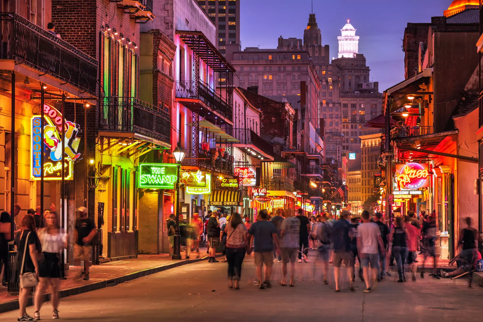 Crowds of people walk along Bourbon St in the French Quarter in front of bars and restaurants, in New Orleans, Louisiana, USA.