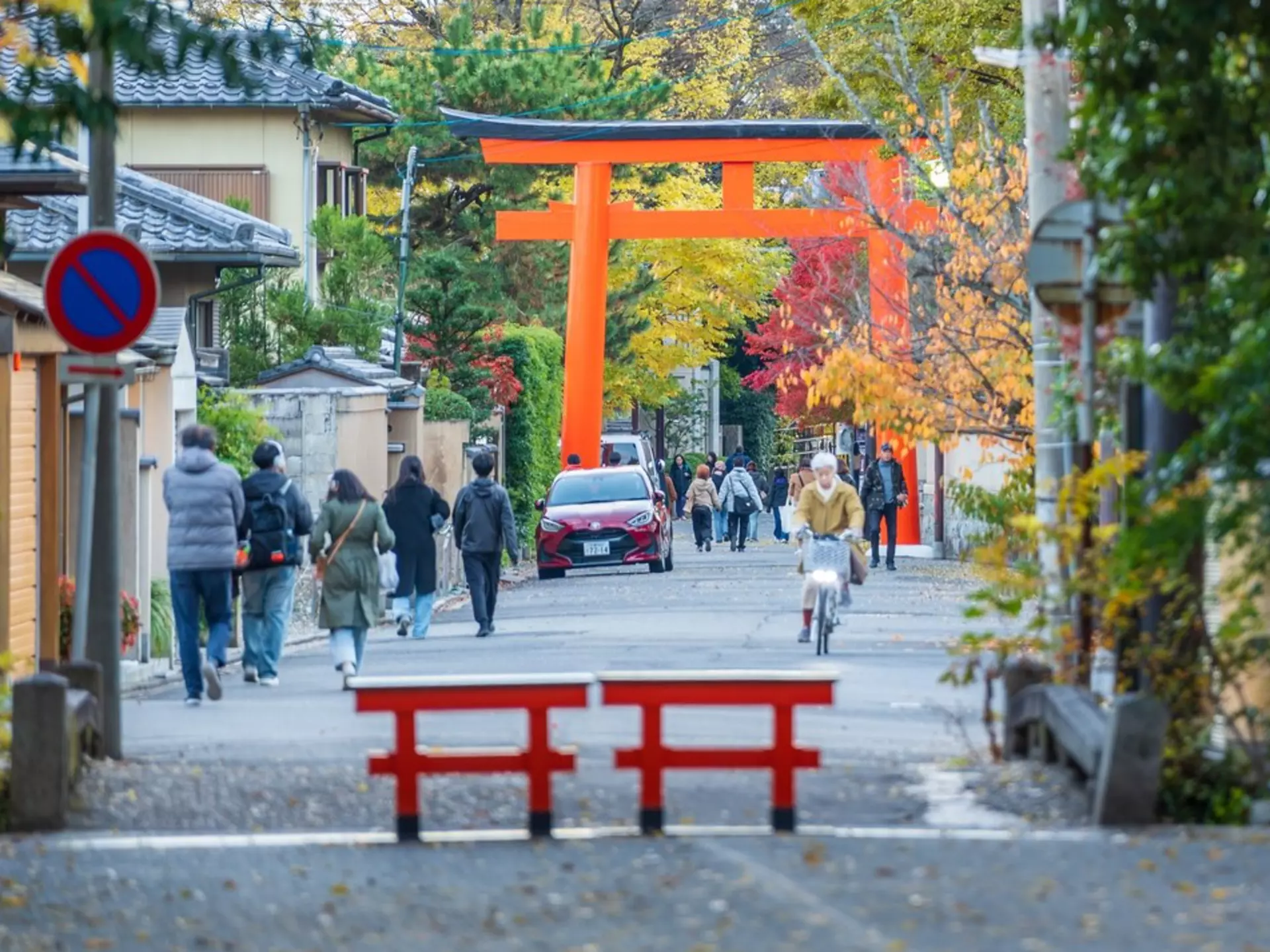 Red gates on a path lined with trees showing fall foliage