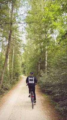 A cyclist rides down a dirt trail through a forested park in Helsinki.