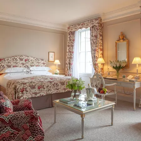 A luxury hotel bedoorm with flower-prints on the bedding and curtains.