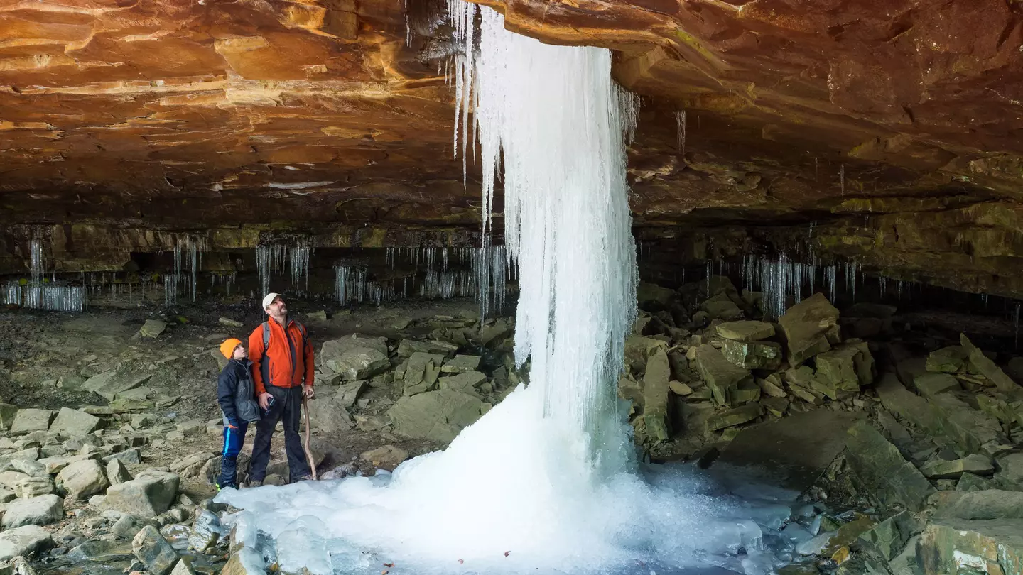 Father and son looking at the frozen waterfall at Glory Hole Falls, Arkansas, USA