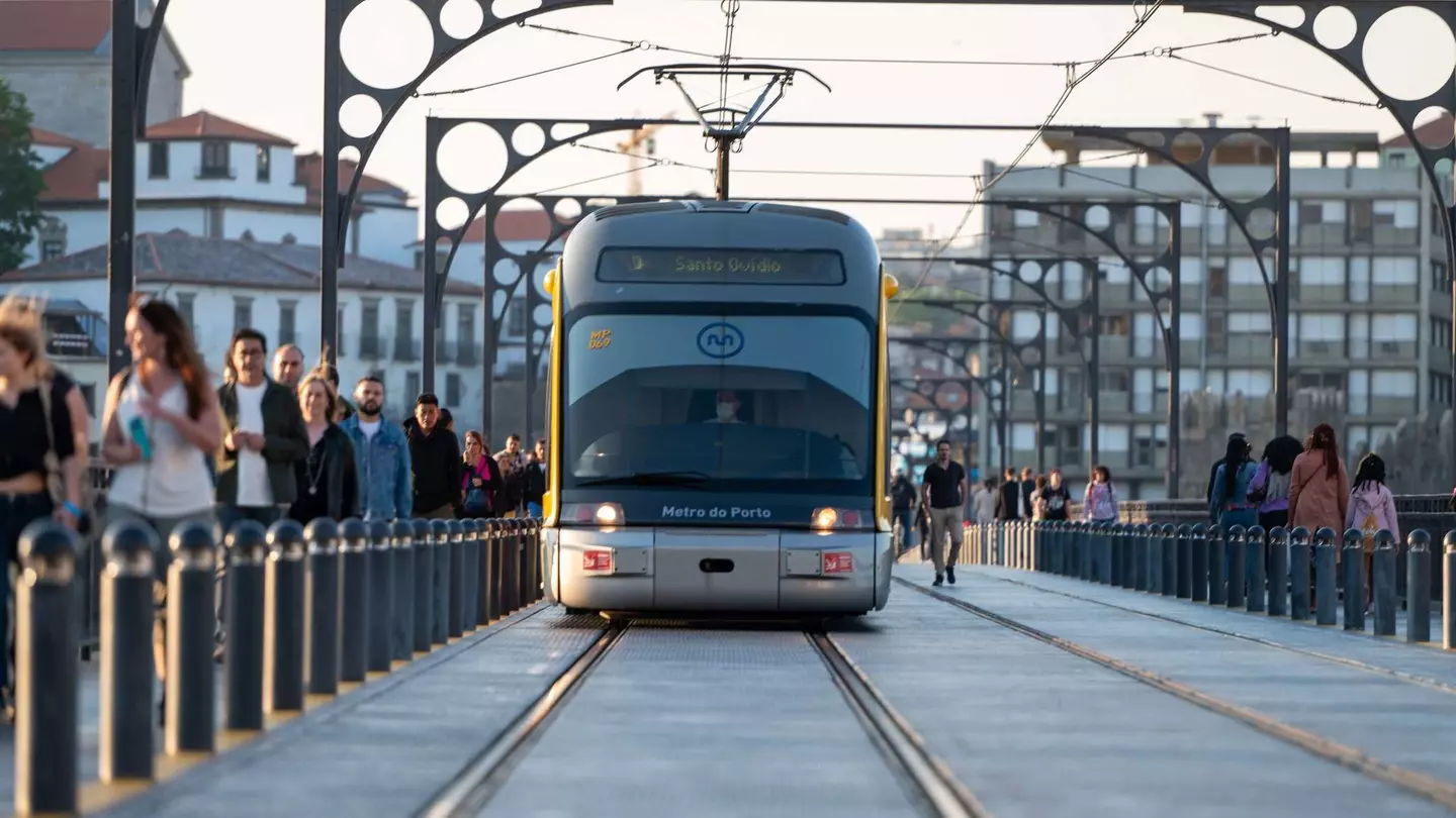 People walking past the Metro de Porto on the bridge over the Douro Luis II river in Porto, Portugal in the summer of 2022.