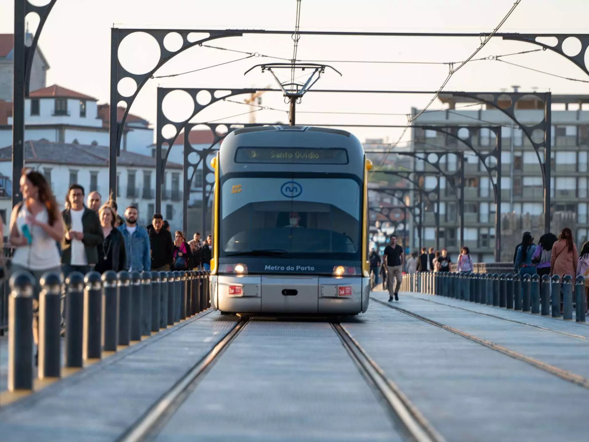 People walking past the Metro de Porto on the bridge over the Douro Luis II river in Porto, Portugal in the summer of 2022.