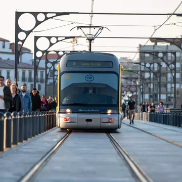People walking past the Metro de Porto on the bridge over the Douro Luis II river in Porto, Portugal in the summer of 2022.
