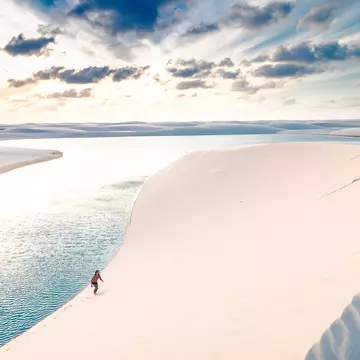 Young man climbing the sand dunes of Lençois Maranhenses.