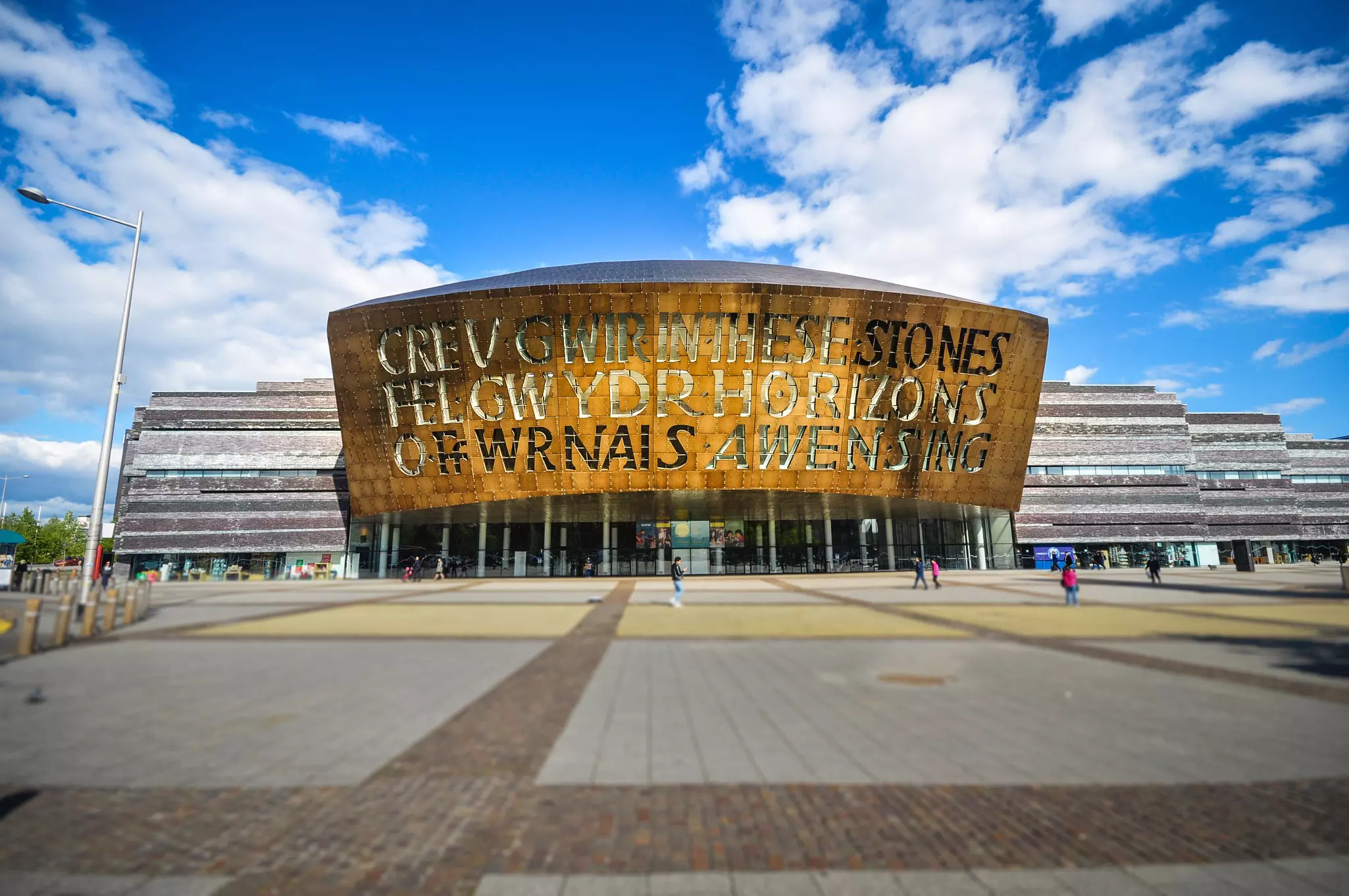 The exterior of a large theater with a bronze fronting with Welsh writing on it