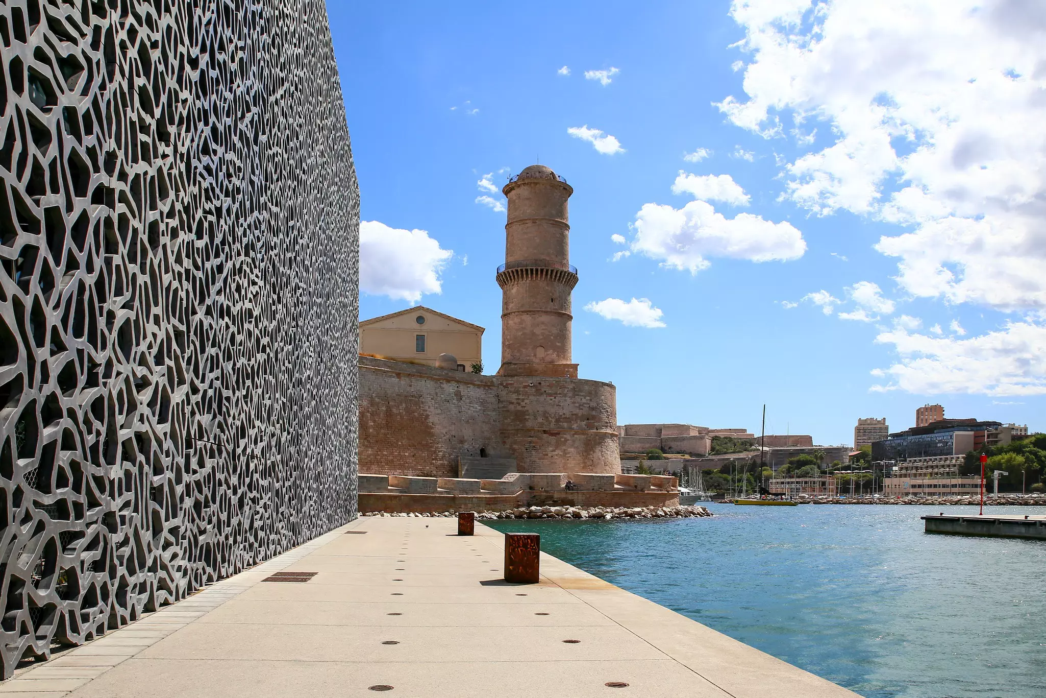 A modern harborside building and a historic fortress.