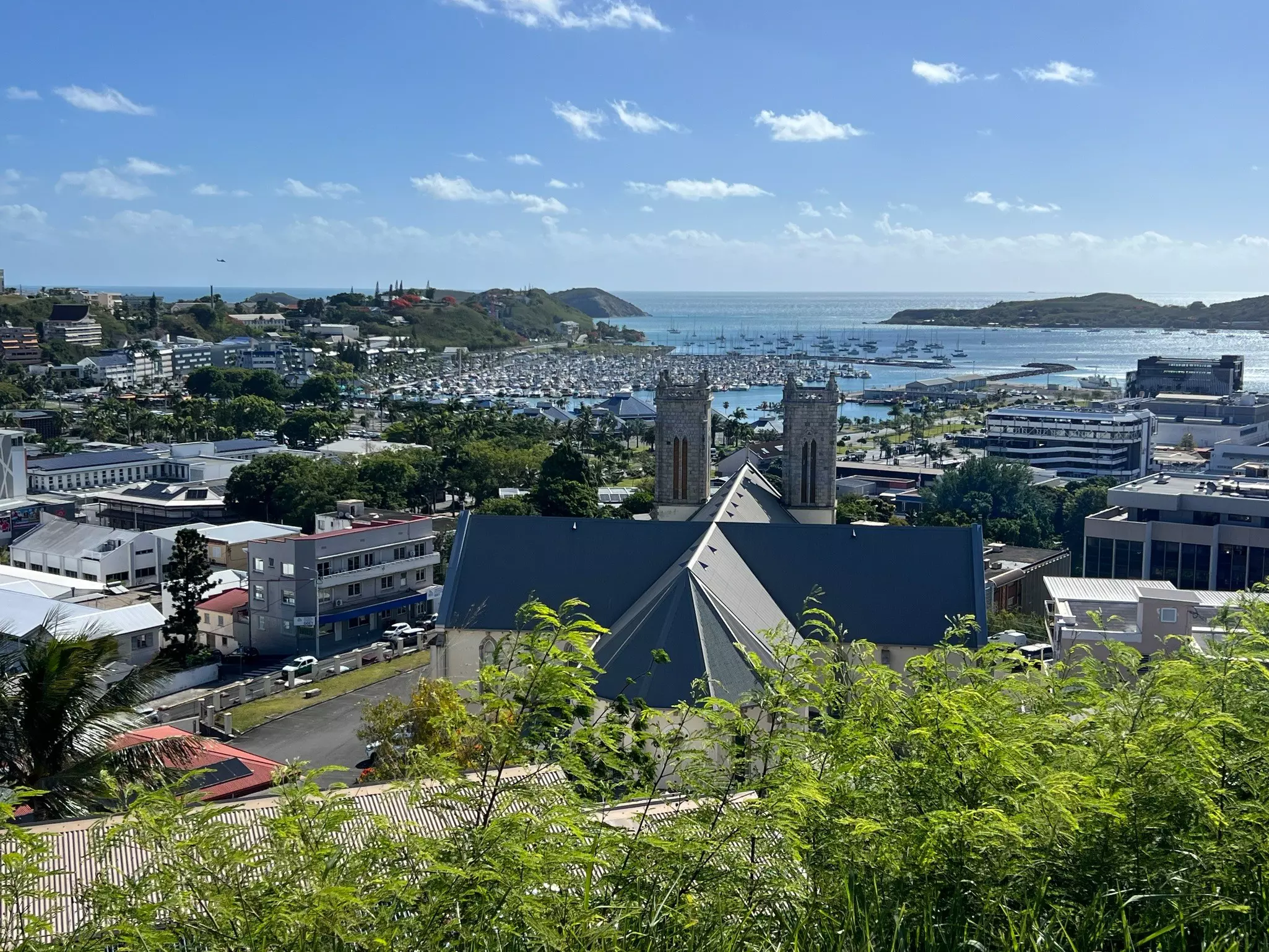 A small city seen from a viewpoint, with a chuch and boats in the harbor.