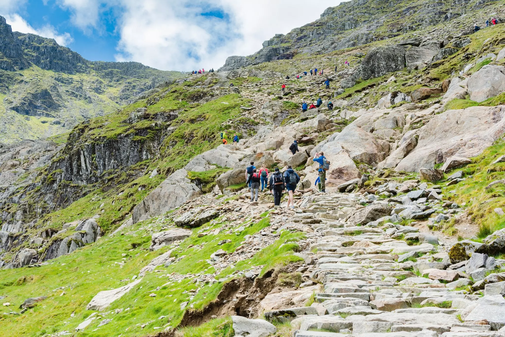 Snowdonia, Wales: People Climbing up the mount Snowdon in North Wales, view of the stone path, mountains, green grass
