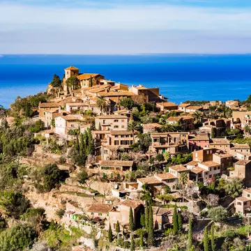 A gorgeous hilltop village bathed in sunshine with the sparkling blue of the ocean in the distance.
