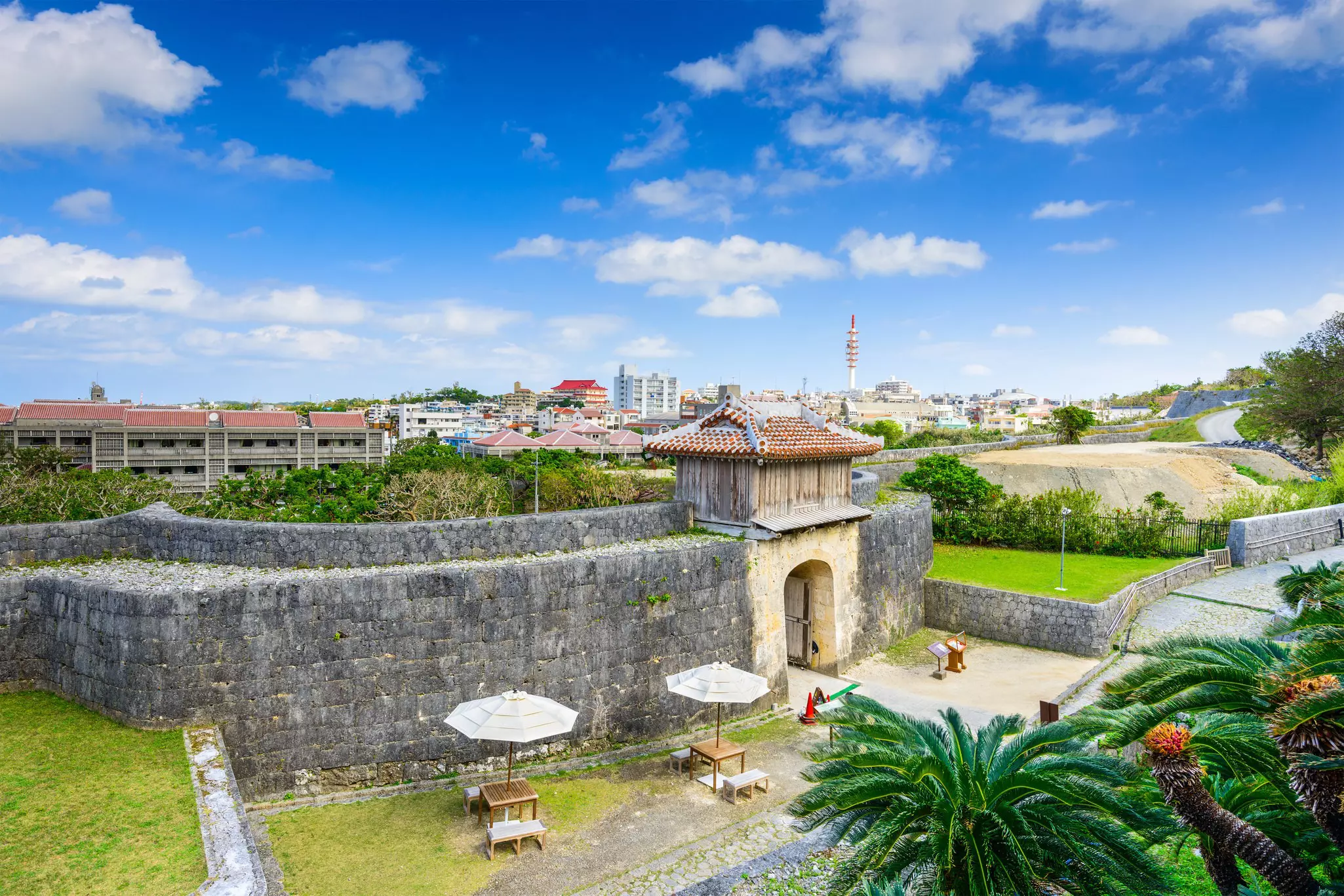 A solid stone castle wall and gateway on the edge of a city.
