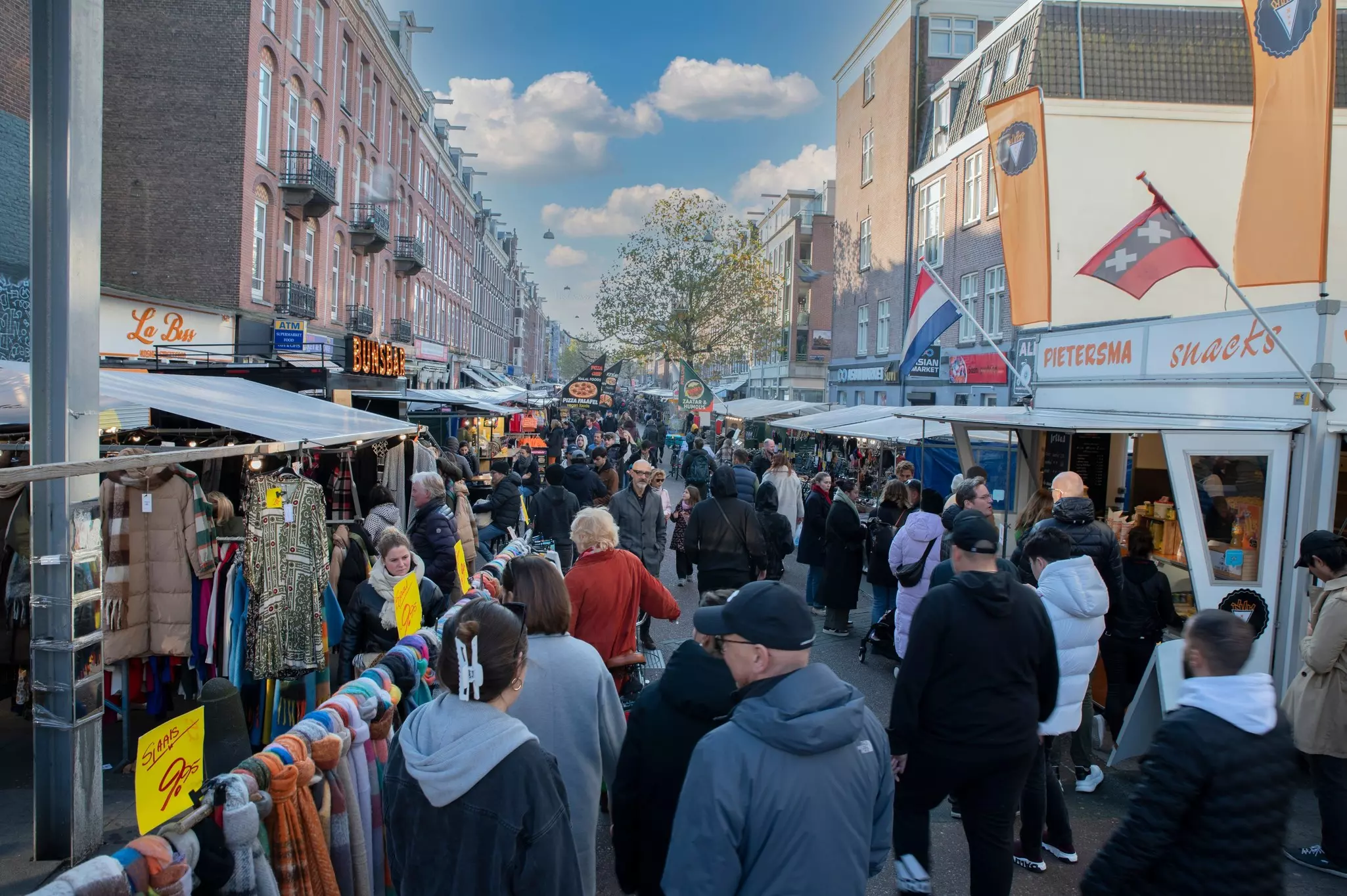 A street market crowded with people looking at stands on either side.