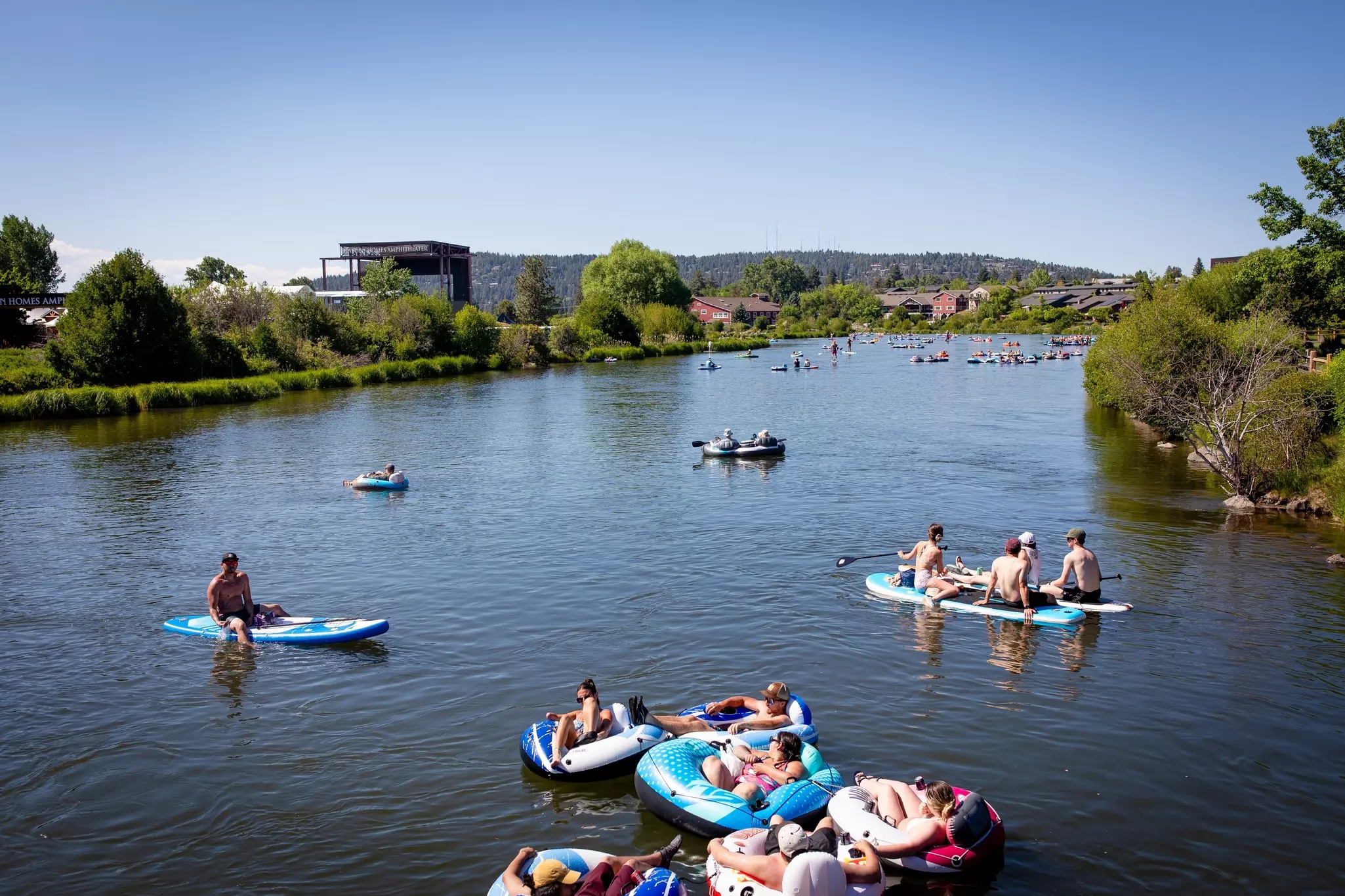 People tubing down the Deschutes River in Bend as it flows past the Old Mill District.