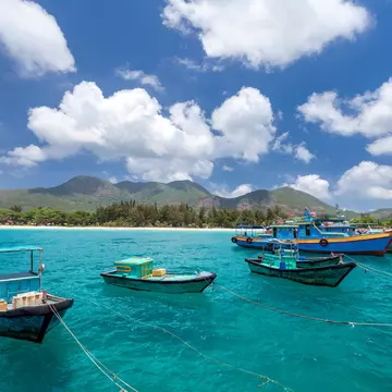 Vietnamese fishing boats on a tropical Con Dao Island. View from the pier in the direction of a beach with white sand. Aleksander Kaczmarek / Getty Images